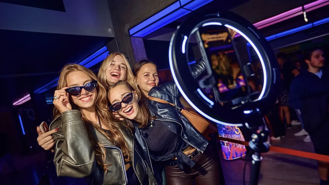 Fiatalok napszemüvegben pózolnak a 360°-os szelfigép előtt egy bulin