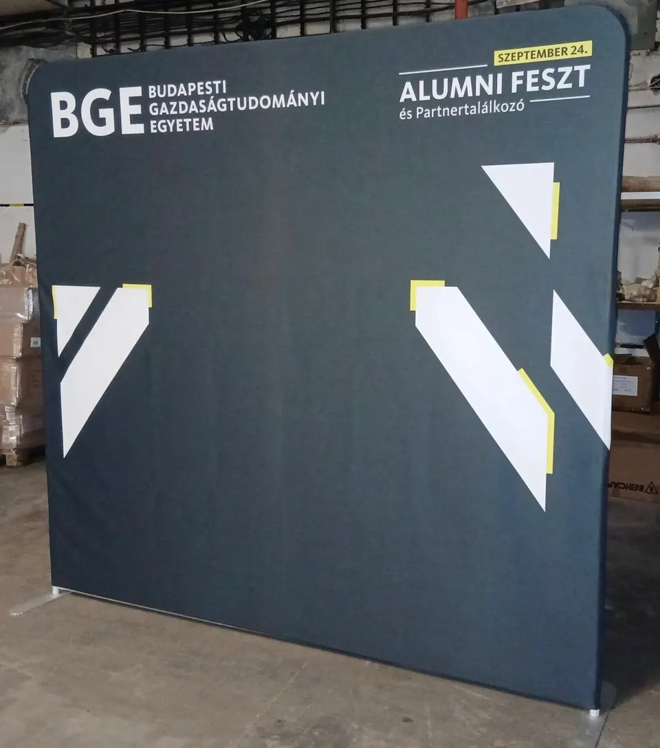Egyedi háttérfal a BGE Alumni Feszt és Partnertalálkozóra: sötétkék fal a BGE logójával, a rendezvény nevével és dátumával