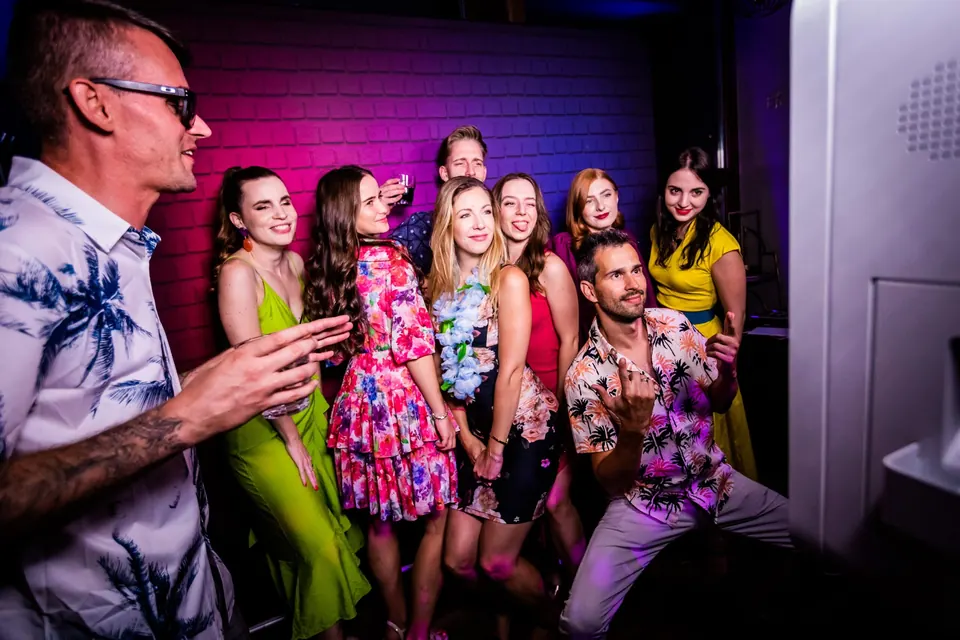 Céges parti vendégei csoportképhez állnak neon fényben