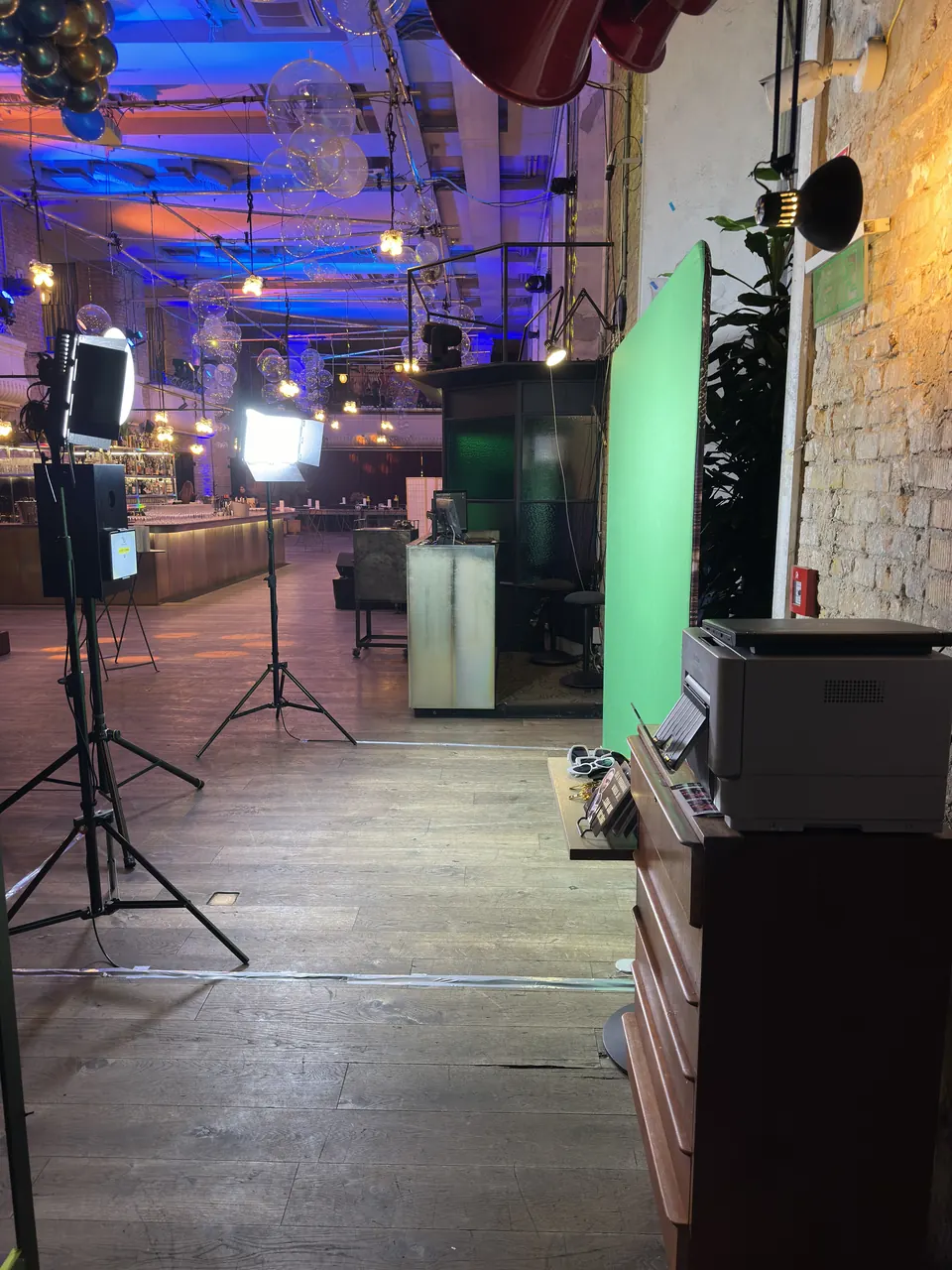Zöld hátteres fotós szett lámpákkal, nyomtatóval és kellékasztallal egy loft-helyszínen